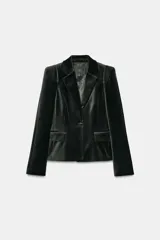 Blazer entallada de Zara Woman Collection confeccionada en tejido de terciopelo. Presenta cuello con solapas de muesca, manga larga con hombreras, bolsillos delanteros con solapa y cierre frontal con un botón. Incluye forro interior.