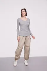 Remera blanca de manga larga, entallada, con cuello redondo y una hilera de botones en el frente. Incluye un pequeño bolsillo decorativo en el pecho.