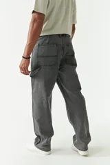 Jean estilo carpenter de corte relajado, recto y amplio, con diseño de cinco bolsillos y costuras reforzadas características del modelo. Presenta un acabado lavado en tono gris oscuro.