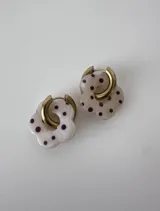 Aros de acero quirúrgico con argolla dorada y dije colgante en forma de flor translúcida con lunares bordó.