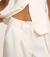 Pantalón de vestir blanco, de corte recto, con trabillas en la cintura, cierre oculto y pliegues.