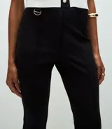 Pantalón de corte flare confeccionado en punto roma, con cintura estructurada, detalle de hebilla decorativa, cierre frontal y bolsillos posteriores.