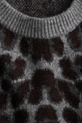 Buzo oversized de punto jacquard con estampado de leopardo, cuello redondo acanalado y hombros caídos. Presenta puños y bajo con terminación acanalada.