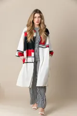 Túnica larga color marfil con vivos negros de satén, bolsillos laterales y diseño geométrico con bloques de color rojo y negro.