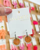 Aros colgantes con gancho de acero, con pieza circular color naranja con borde de strass plateado.