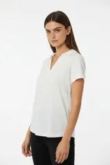 Remera de algodón color blanco, con cuello polo y escote en V, de manga corta y diseño holgado.