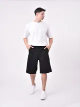 Bermuda de jean color verde claro lavado, corte recto y largo hasta la rodilla. Presenta costuras visibles y bolsillos tipo cargo en los laterales.