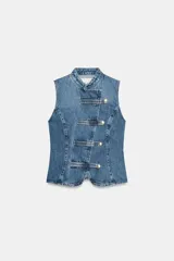 Top de denim blanco sin mangas, con cuello mao y cierre frontal cruzado con trabillas y botones metálicos.