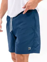 Short de baño de microfibra negro, con cordón blanco ajustable en la cintura, bolsillos laterales y un bolsillo trasero con tapa. Presenta un pequeño parche cuadrado con un logo en la parte inferior del muslo izquierdo.