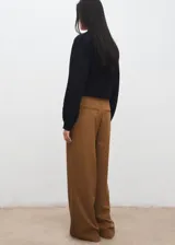 Pantalón de vestir color marrón, de corte amplio y fluido, con tiro alto y diseño recto de perneras anchas.