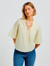 Blusa color amarillo claro de algodón con escote en V y mangas 3/4 acampanadas.