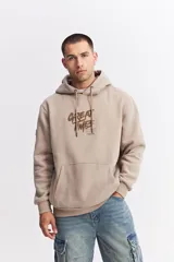 Canguro oversize color beige, con capucha ajustable mediante cordones, bolsillo frontal tipo canguro y estampa gráfica frontal con la frase 'GREAT TIMES' y logo de la marca.