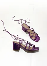 Sandalias de tacón cuadrado color fucsia metalizado, con tiras finas que se atan alrededor del tobillo.