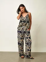 Pantalon tipo palazzo color negro con estampado paisley en tonos beige y blanco, corte holgado y tiro medio.