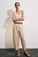 Pantalón tiro bajo color marrón, de corte globo y pernera recta con raya marcada al frente. Incluye trabillas y un cinturón marrón oscuro con hebilla metálica.