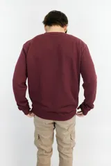 Buzo de punto color bordó, de corte clásico y manga larga. Presenta un pequeño logo bordado en el pecho.