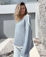 Sweater de tejido de punto en color gris con detalles de bordes en color blanco, de corte holgado y mangas largas.