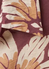 Camisa de manga larga color marrón con estampado floral grande en tonos beige y blanco, cuello camisero y cierre frontal con botones.
