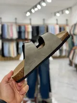 Sandalias de dos tiras negras con hebillas metálicas ajustables, plantilla anatómica y suela plana.