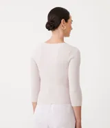 Blusa de punto color lila claro, ajustada al cuerpo, con escote cruzado en V y mangas tres cuartos.
