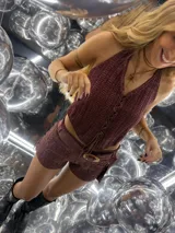 Top negro de tejido de punto con escote halter y lazada frontal ajustable. Presenta un diseño ajustado al cuerpo.