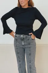 Remera de algodón acanalado color negro, con cuello bote y mangas largas con terminación oxford acampanada.