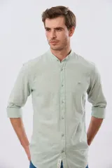 Camisa de lino y algodón color beige, de manga larga, con cuello mao y cierre frontal con botones. Presenta un pequeño bordado al tono en el pecho.