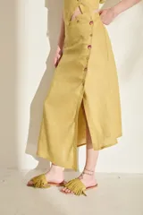 Falda midi verde de lino, con diseño asimétrico, tajito frontal y cierre lateral con botones de madera con ojales bordados.