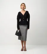 Pollera lápiz de sastrería color gris con finas rayas verticales, cintura estructurada con trabillas, caída recta y una abertura frontal discreta.