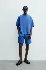 Bermuda de algodón color beige claro, corte relajado (relaxed fit), con cintura elástica ajustable mediante cordón y bolsillos laterales y trasero de plastrón.