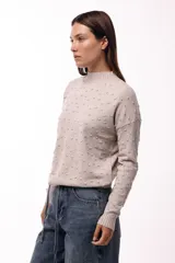 Sweater de tejido de punto color verde oliva, con textura de pequeños relieves circulares, cuello redondo y mangas largas con puños acanalados.