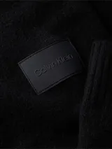 Sweater negro de lana y acrílico con cuello redondo, puños y bajo de canalé. Tiene una insignia con el logo de Calvin Klein en la manga.
