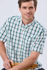 Camisa de manga corta a cuadros en tonos blanco, azul y gris, con cuello abotonado, bolsillo en el pecho y cierre frontal con botones.