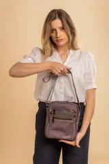 Morral bandolera color lila con correa ajustable, dos bolsillos frontales con cierre y dos bolsillos internos.