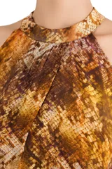 Vestido largo de viscosa con estampado animal print tipo serpiente en tonos tierra. Presenta un diseño fluido con cuello halter y abertura frontal, ideal para un look sofisticado.