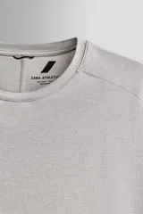 Remera de entrenamiento regular fit de Zara Athleticz, confeccionada en tejido técnico verde melange con estructura, ligero y elástico. Cuenta con tecnología Quick Dry nivel 2, cuello redondo, manga corta, costuras planas y detalle de logo estampado.