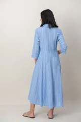 Vestido midi cruzado de seda con estampado de rayas celestes y blancas, escote en V con solapa, mangas tres cuartos y detalle de nudo drapeado en la cintura.