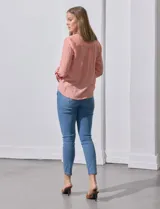 Blusa blanca de gasa marca Zac & Rachel, con cuello a la base, escote en V, abertura central con botones, bolsillo aplicado en el pecho y mangas largas regulables con presilla y botón. Tiene terminación opcional de nudo en el ruedo.