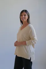 Sweater de punto color crudo, con escote en V, manga larga y diseño holgado con costura central vertical.