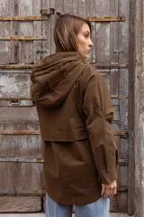 Gabardina liviana color beige con capucha, cierre frontal oculto y cintura ajustable mediante cordón. Presenta bolsillos delanteros amplios y mangas largas con puños rectos.