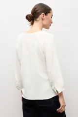 Blusa negra de manga larga con diseño de tejido plumeti y escote en V.