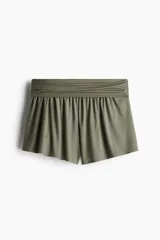 Short de mujer color verde militar, confeccionado en tejido de punto acanalado fino de viscosa. Presenta una cintura ancha fruncida que genera un efecto drapeado en la parte inferior.