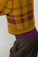Jersey de punto con cuello perkins y manga larga, diseño a cuadros en tonos mostaza y marrón con detalles de costuras en color amarillo neón.