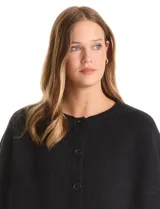 Capa de punto color bordó con diseño envolvente de doble capa superpuesta. Presenta cuello a la base, cierre frontal con botones y mangas estilo japonés con terminaciones acanaladas.