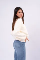 Sweater de punto liso en color beige, con cuello redondo, mangas largas y calce relajado.