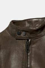 Cazadora de piel con cuello subido, manga larga y cierre frontal con cremallera metálica y botones a presión.