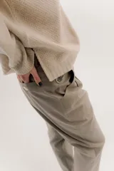 Pantalón sastrero de tiro medio, color gris oscuro con rayas verticales finas. Presenta pinzas delanteras, bolsillos delanteros con pin bordado y bolsillos traseros tipo vivo.