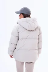 Campera puffer de corte holgado en color beige, con capucha integrada, cierre frontal completo y bolsillos laterales. Presenta un diseño acolchado con acabado mate y puños elásticos.