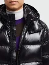 Campera puffer corta de Moncler, modelo Maya, con acabado brillante, capucha desmontable y cierre frontal con cremallera. Presenta bolsillos laterales y un bolsillo con solapa en la manga izquierda.