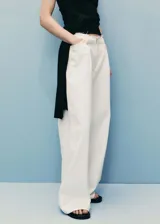 Pantalon de denim color crudo con diseño wide leg, tiro medio y cintura con detalle deshilachado. Cuenta con cinco bolsillos, trabillas para cinturón y cierre frontal con cremallera, botón y ganchos ocultos.